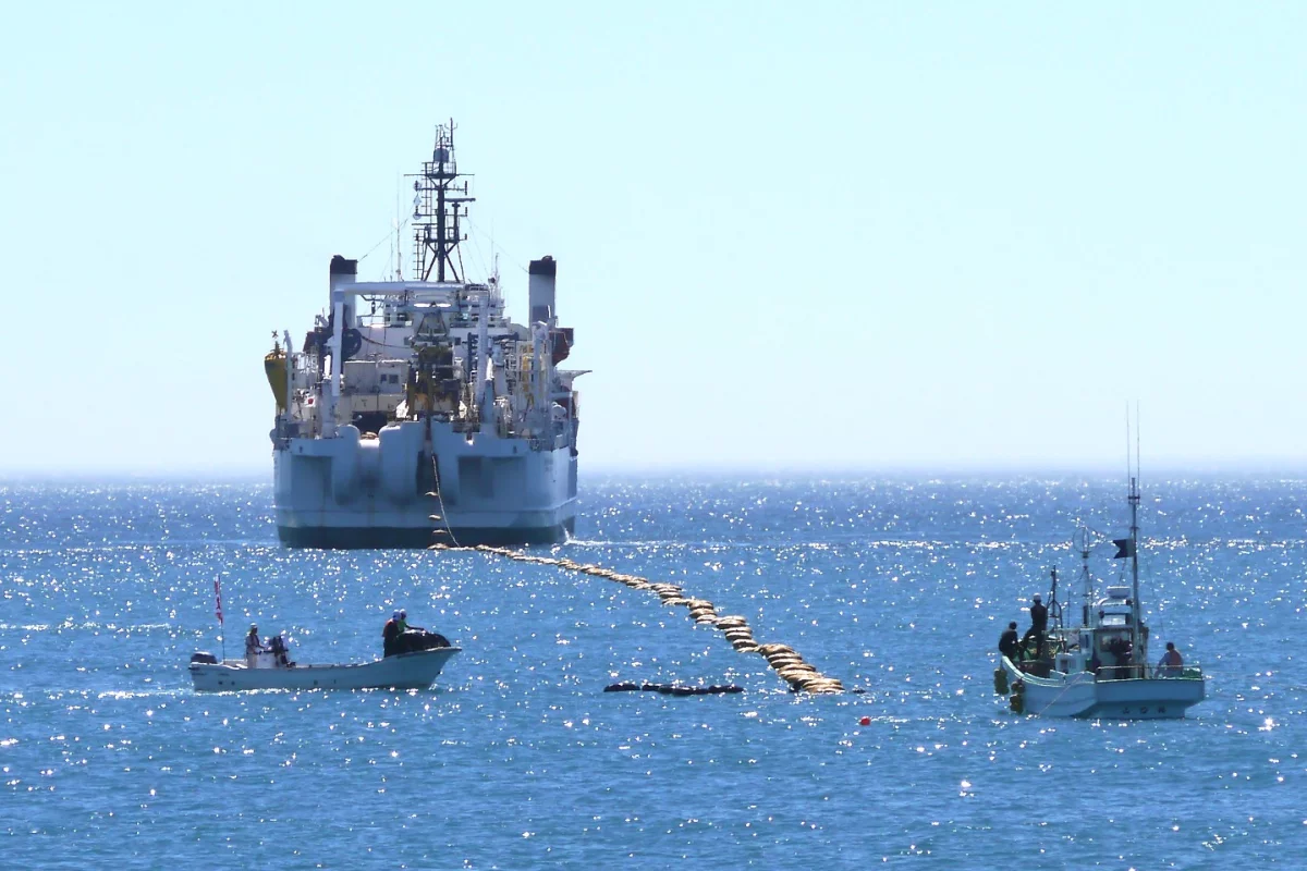 The brown bag-like objects are floats that hold the cable up so it doesn't drag on the ocean floor – they are removed after the cable is run