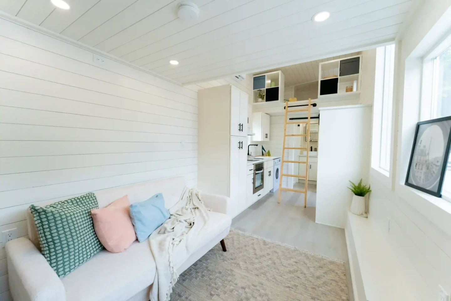 The Vista 24' tiny house's living room includes a sofa, along with a projector and pull-down screen