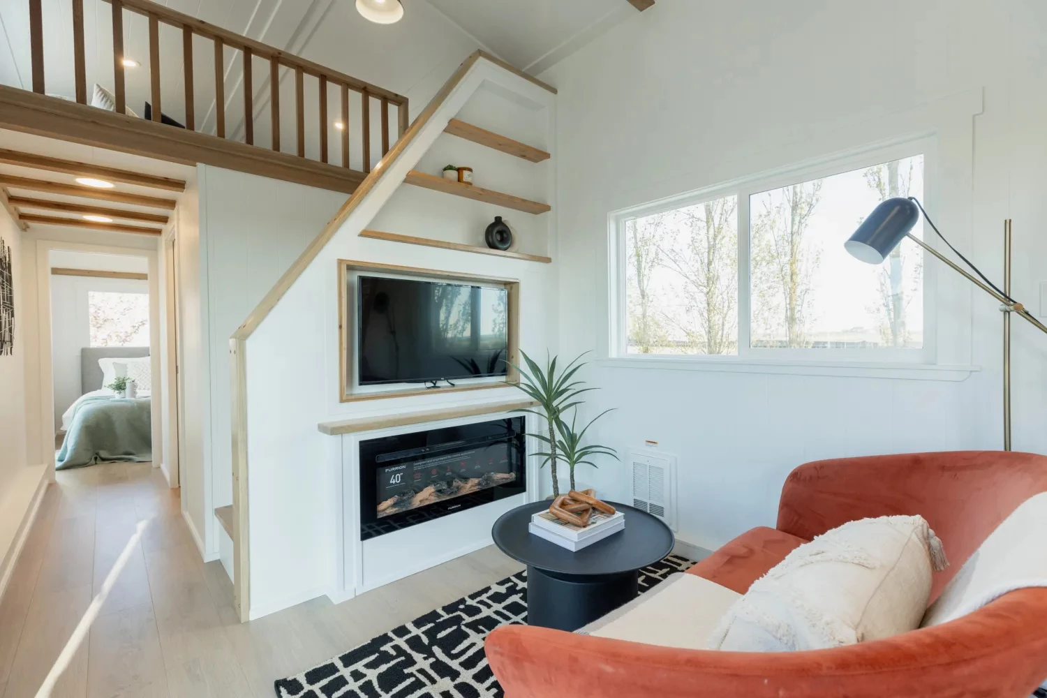 The Ventura Park Model Tiny Home's living room includes some seating and a wall-mounted TV and fireplace