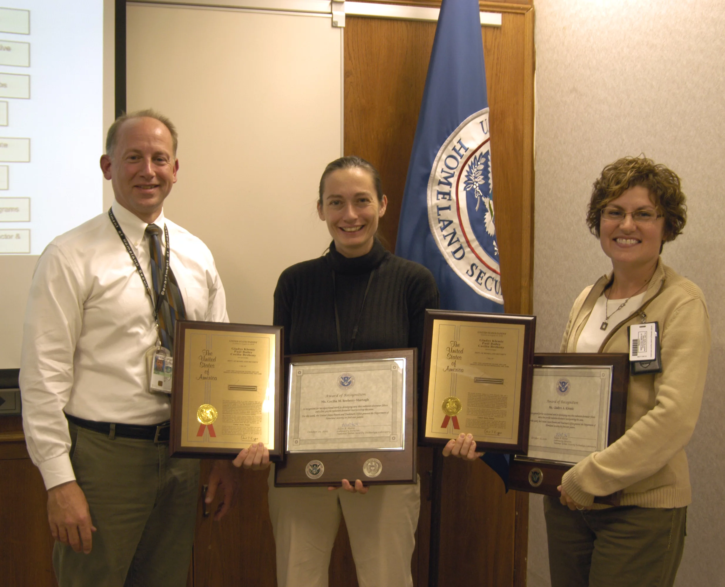 Adam Hutter, Director of NUSTL, presents Cecilia Murtagh (center) and Gladys Klemic with plaques commemorating Homeland Security's first patent, for the Citizen's Dosimeter (Photo: Jenny May)