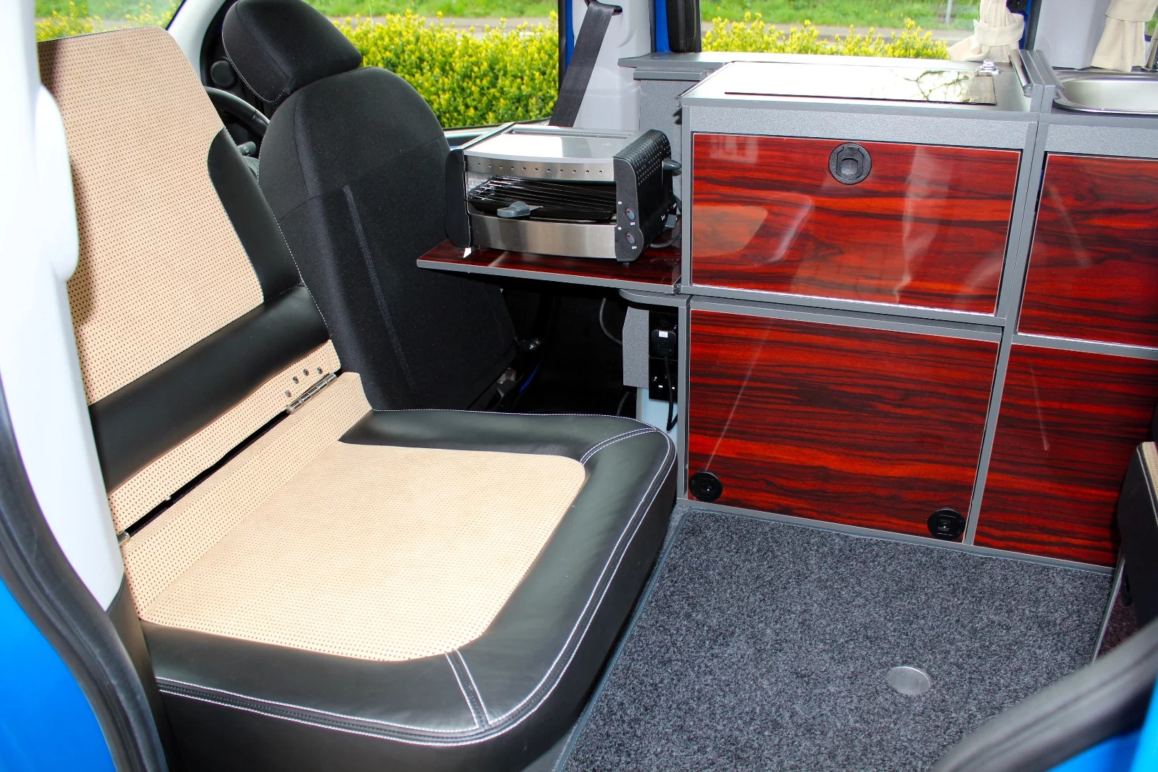 The rear seat folds during travel, allowing the front seats to slide back, then unfolds at camp, creating a lounge seat and bed