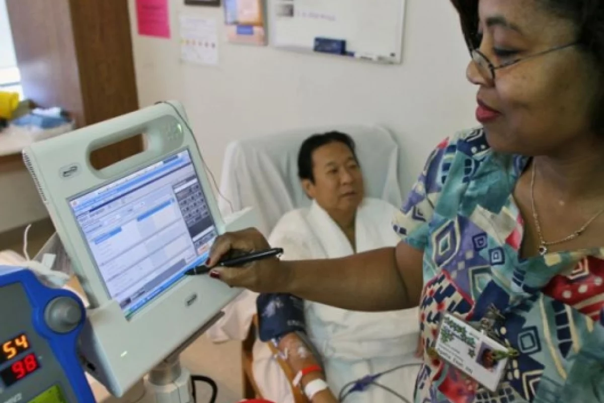 Nurse Agatha Ekeh, right, updates patient Charles Khim's medical record using Motion Computing's C5, the first product based on Intel's mobile clinical assistant platform, Tuesday, Feb. 20, 2007, at UCSF Medical Center in San Francisco.