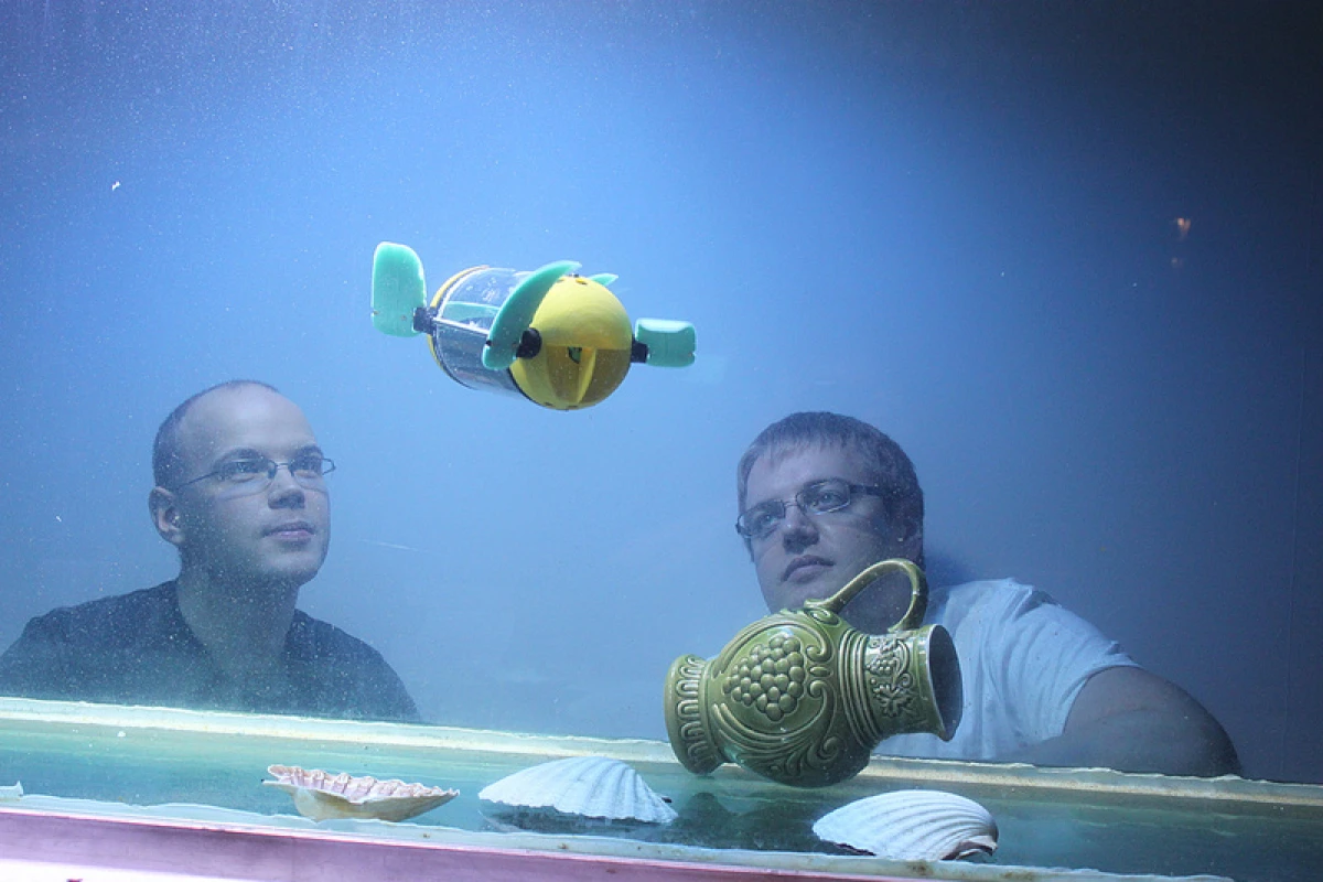 Tallinn University of Technology researchers Asko Ristolainen and Taavi Salumäe watch the U-CAT robot in an aquarium