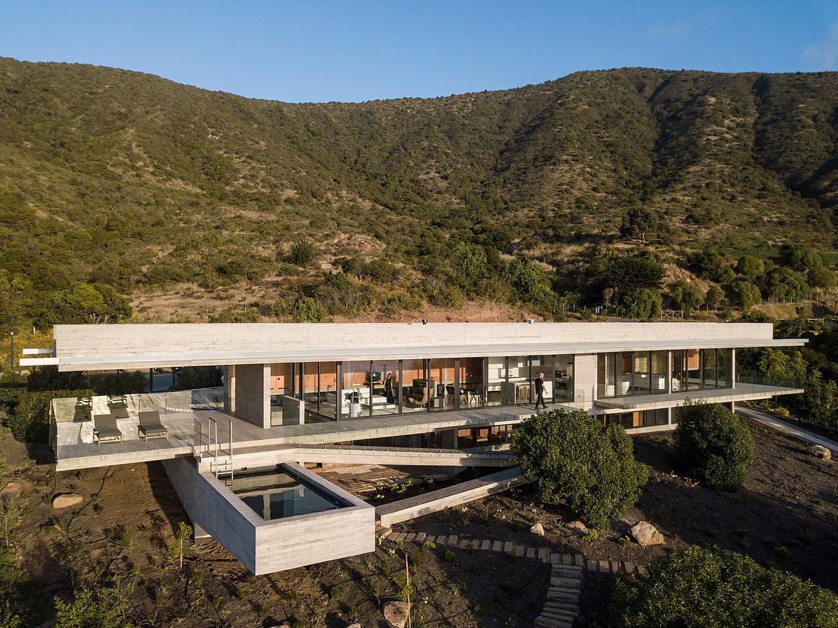 The pool at La Casa H can be accessed via the upper balcony and is housed inside a cantilevered concrete wedge that runs beneath the upper story and presents a sunken entranceway on the other side