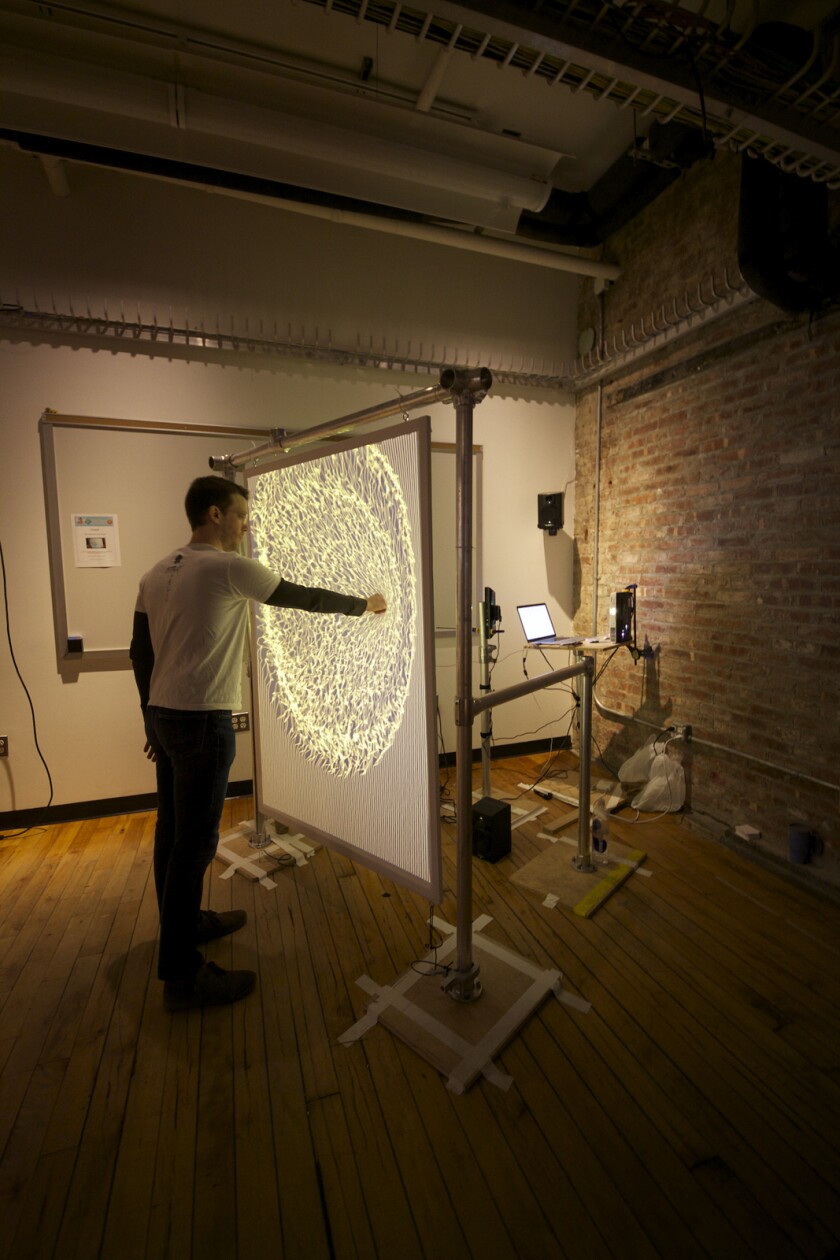 The spandex sheet is mounted within a wooden frame, which hangs from a metal pole frame with a Kinect and an Epson projector positioned behind