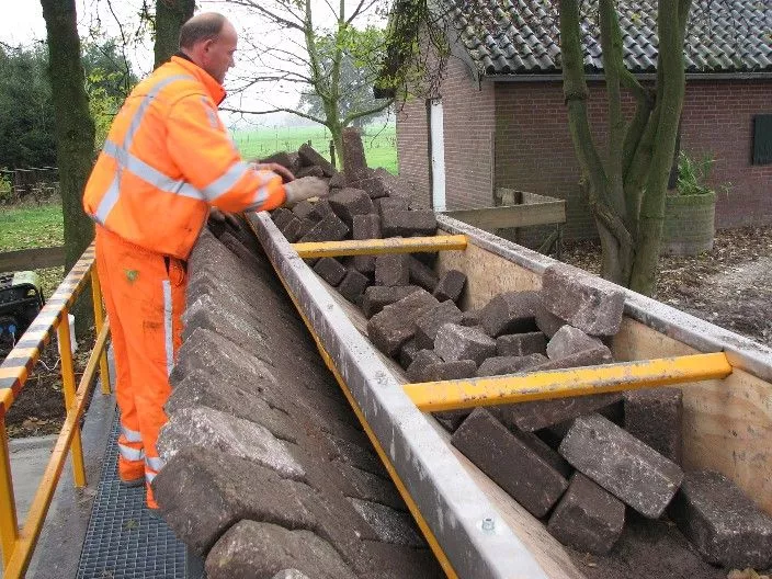 A worker transferring bricks from the hopper to the pusher