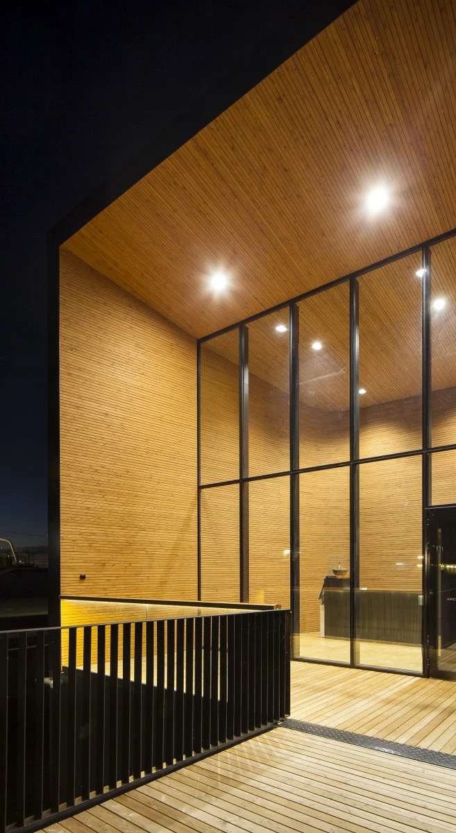 The building's cold and rigid exterior is in stark contrast to its warm interior, which boasts soft curves and an abundance of wood