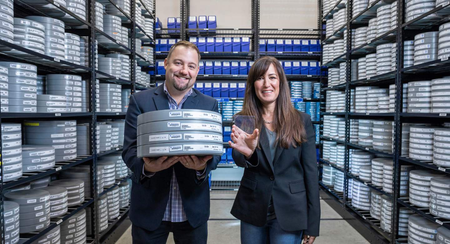Brad Collar (left) and Vicky Colf (right), of Warner Bros., compare the differences between storing the same data on reels of film and glass slides