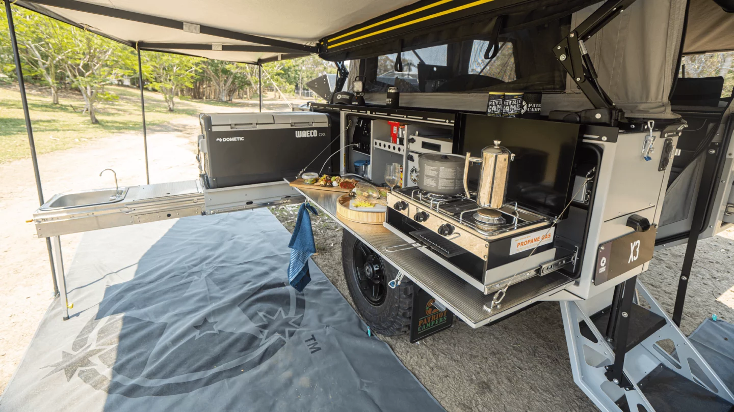 The L-shaped outdoor kitchen includes a long slide-out, fold-down worktop and dual-burner gas stove