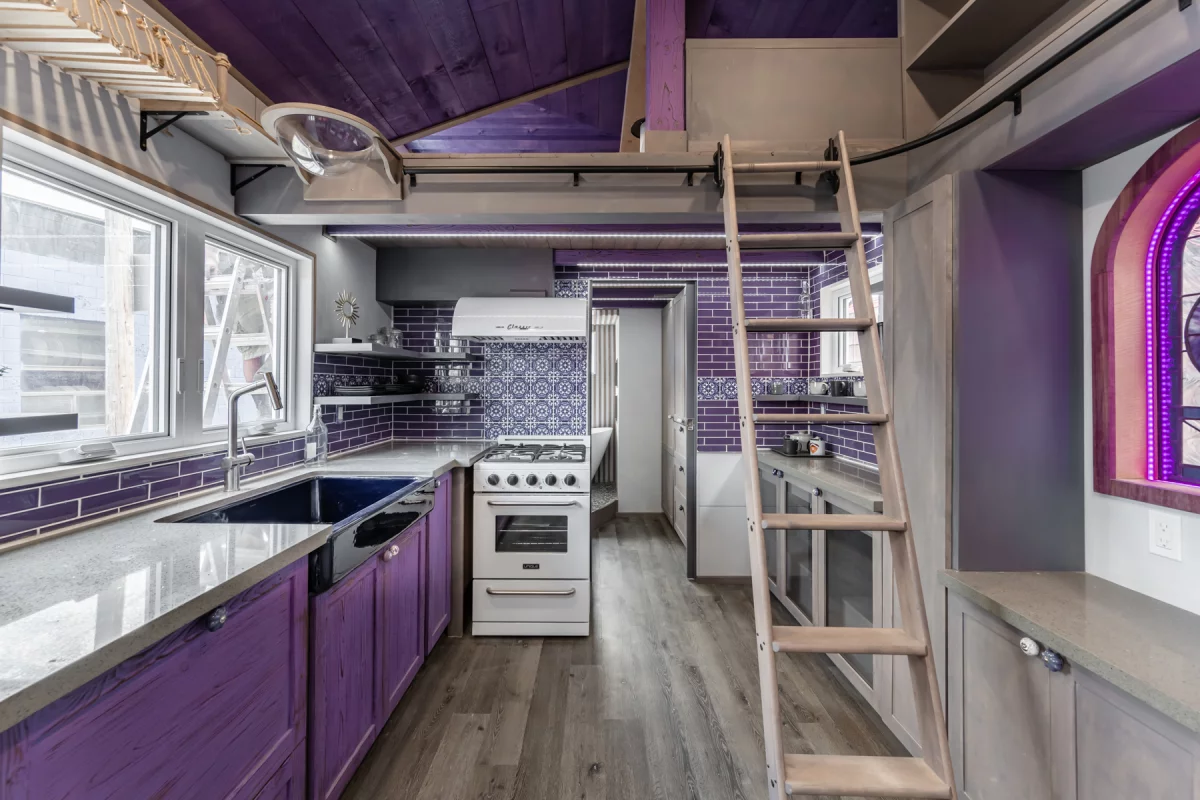 The Purple Heart Manor's kitchen is spacious and includes a large sink, custom cabinetry, a fridge/freezer, and an oven with four-burner propane-powered stove
