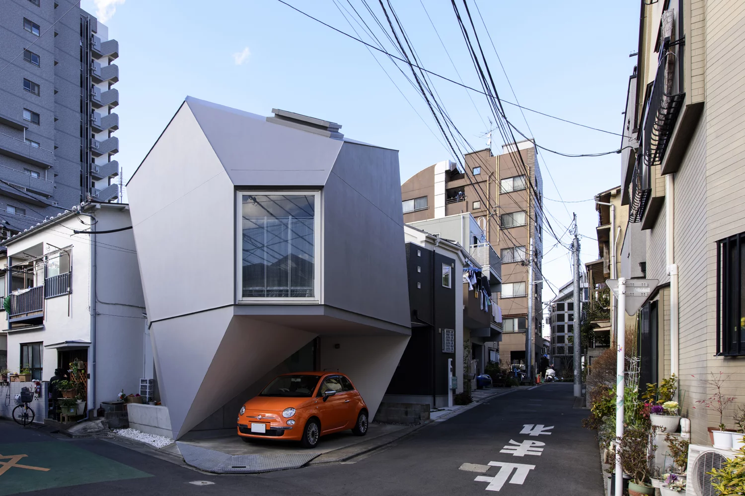 This stunningly bizarre construction was wedged onto the corner of two narrow intersecting streets. The land, only 473 sq ft (44 sq mt), demanded an intricate polyhedron shape to fulfill all the building codes as well as delivering a covered parking space