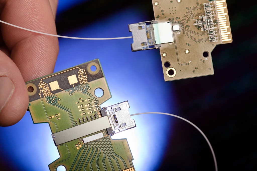 An optical fiber connection is held up to the transmit module of the 50G Silicon Photonics Link