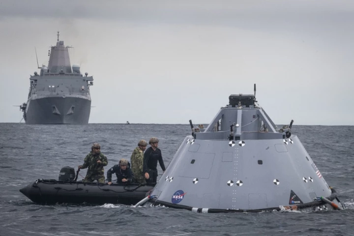 US Navy divers attach tow lines to a dummy Orion capsule