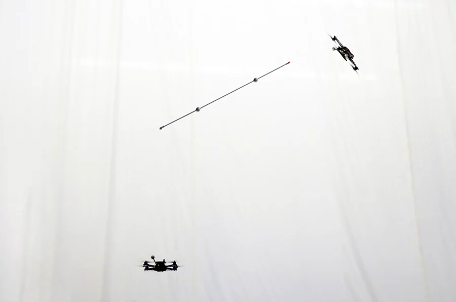 A quadrocopter robot launches a pole into the air while a second robot moves into position to catch it