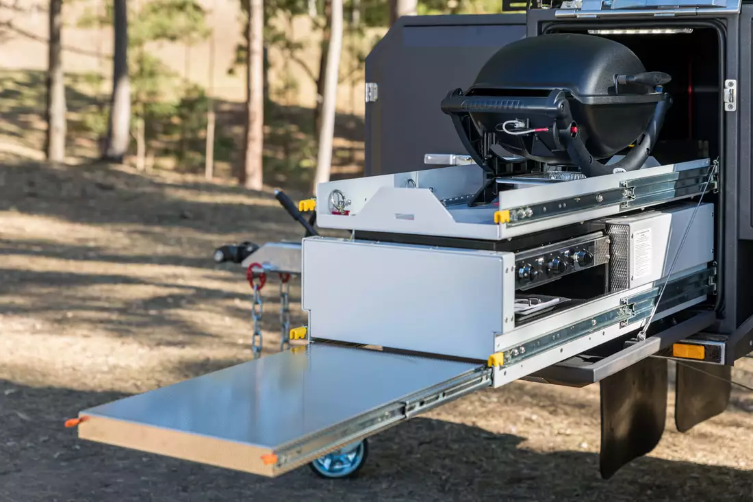 A separate storage slide over the kitchen equipment stores the available Weber Baby Q grill on the commute