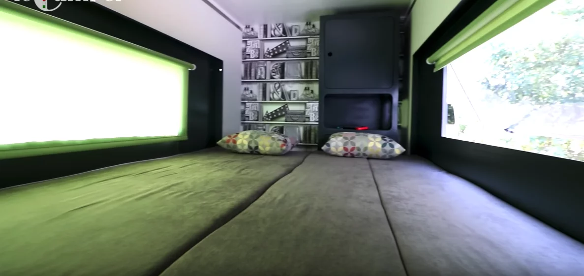 The master bedroom includes a larger bed for two, along with long windows