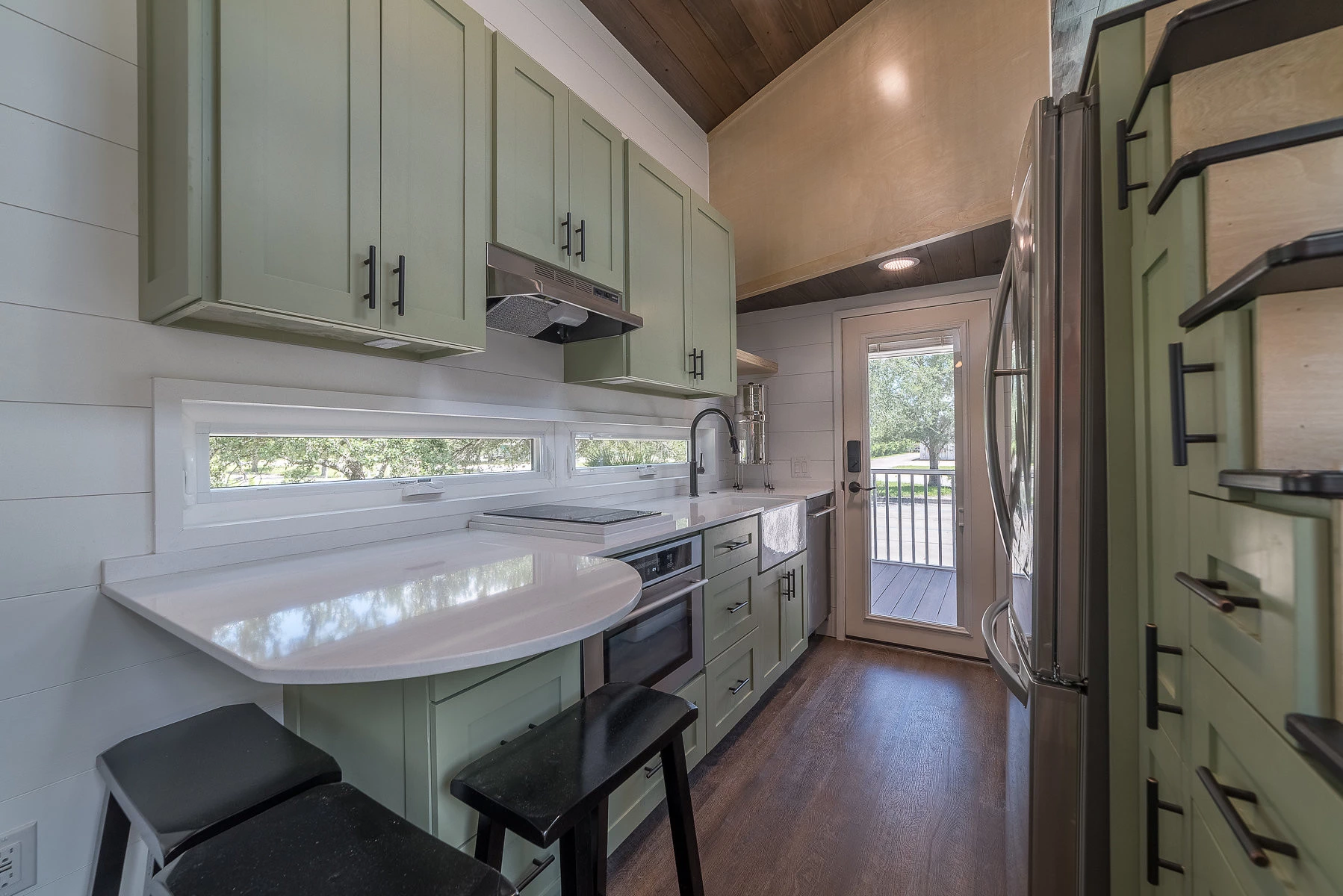 The kitchen is quite exquisite with an oven, countertop induction stove, and a full-size fridge and ample storage. It even features a three person bar at the end of the countertop.