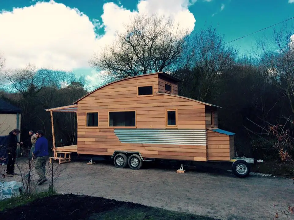 The home sports a curved roof, aluminum siding and small covered porch area