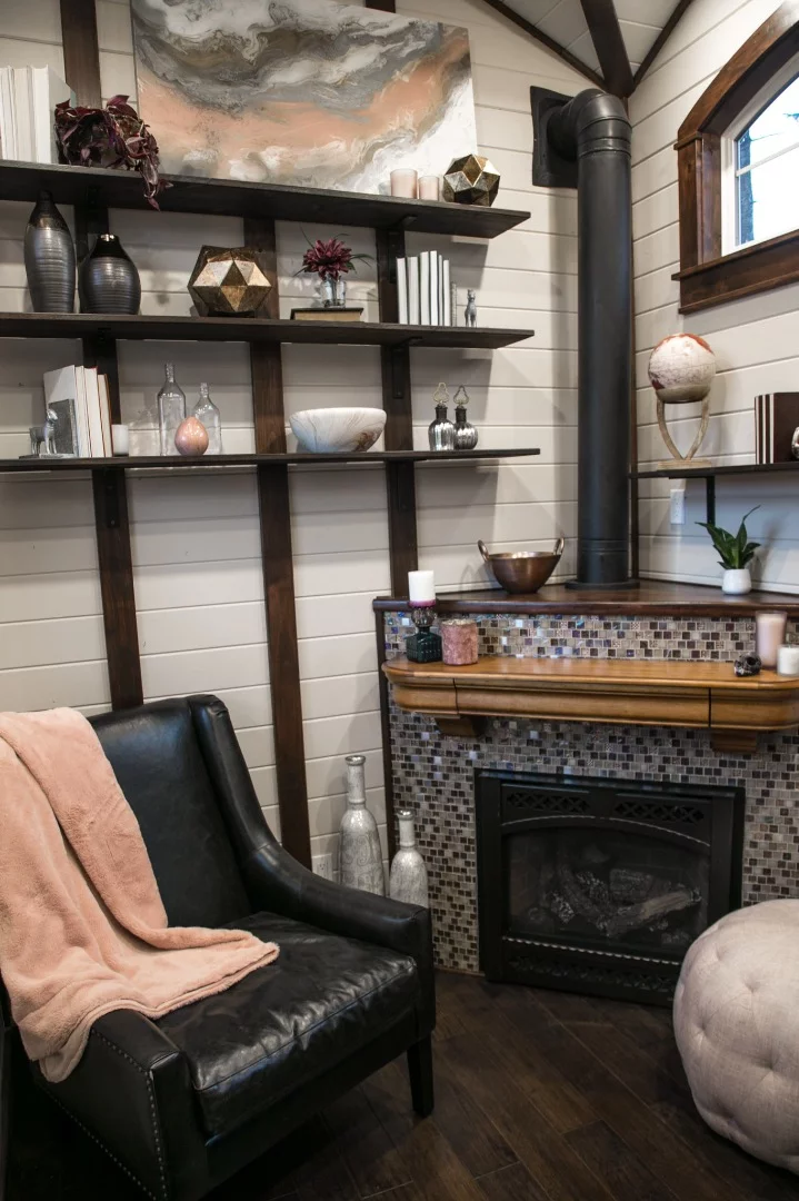 The Tudor-style tiny house is heated by a gas fireplace with mosaic tile surround
