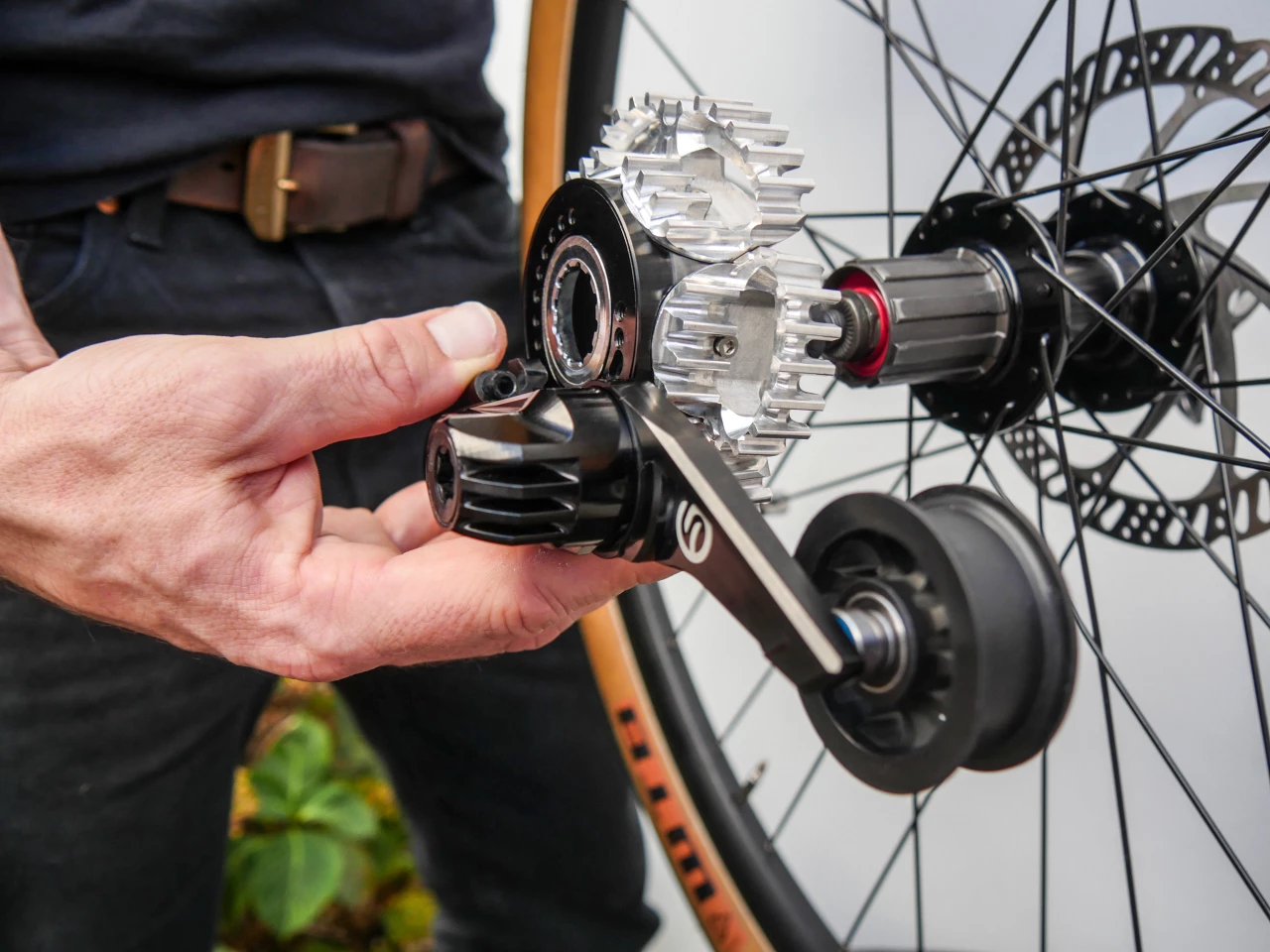 A spring-loaded tensioner wheel takes up belt slack as needed