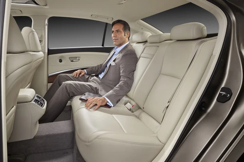 The rear interior of the 2014 Acura RLX with an adult male seated to demonstrate legroom