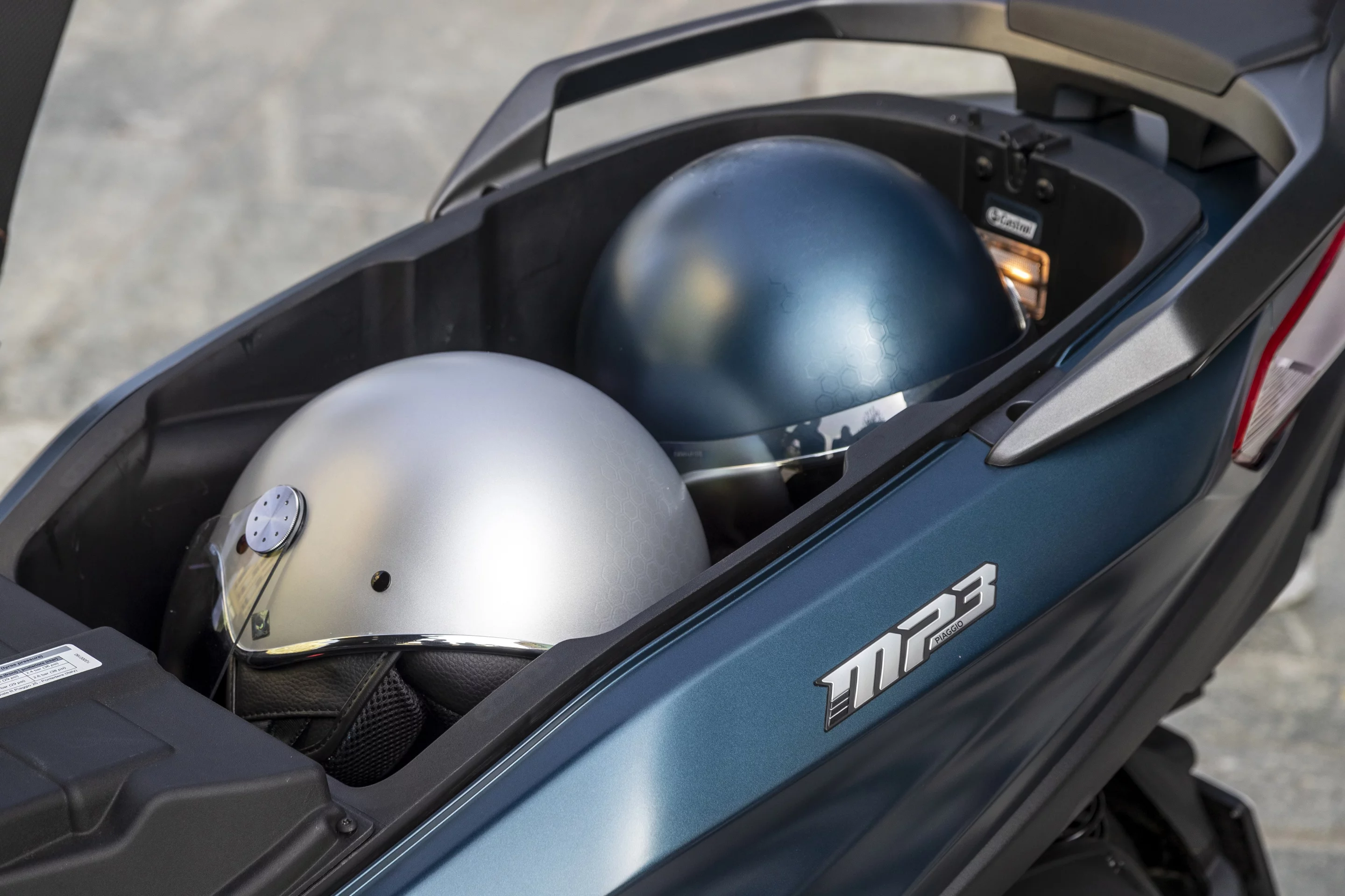 The underseat storage space of the 2022 Piaggio MP3 can accommodate two helmets and is wide enough for a computer bag