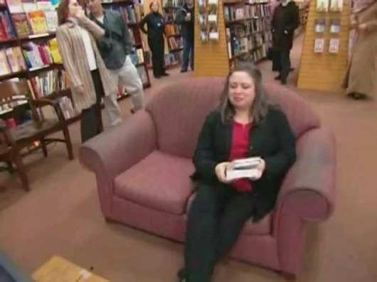 The fan sits comfortably on a couch to meet Margaret Atwood via the LongPen.