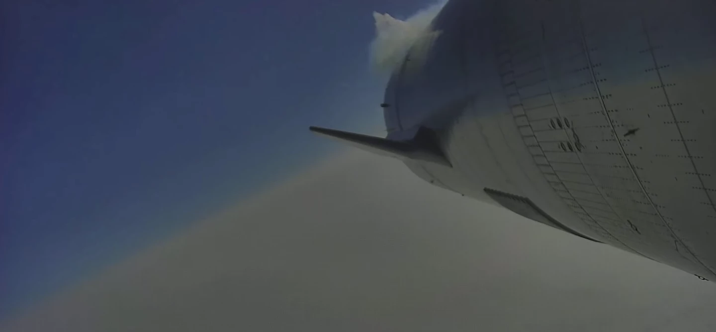 The Starship descends toward Earth using four flaps to guide its path to the landing pad