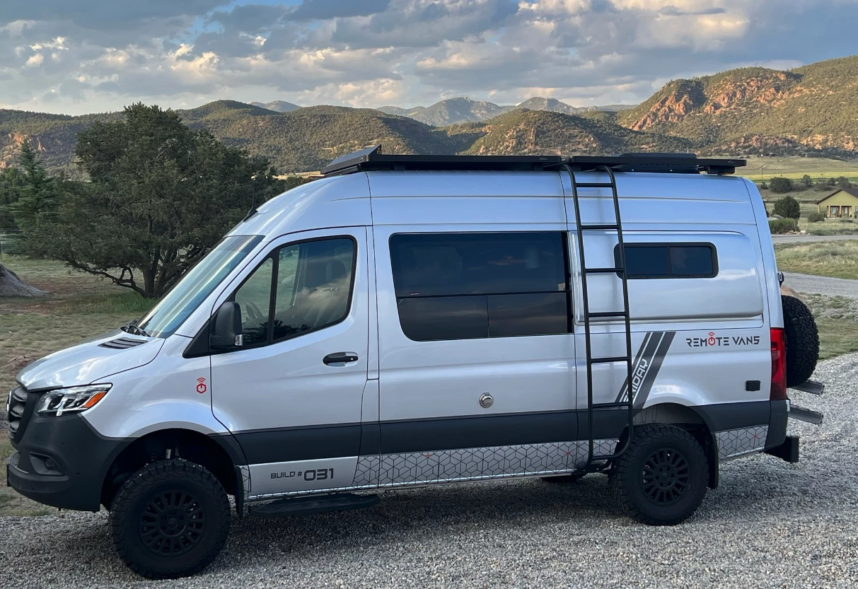 An older pre-2024 Remote Friday camper van poses in front of a mountain vista