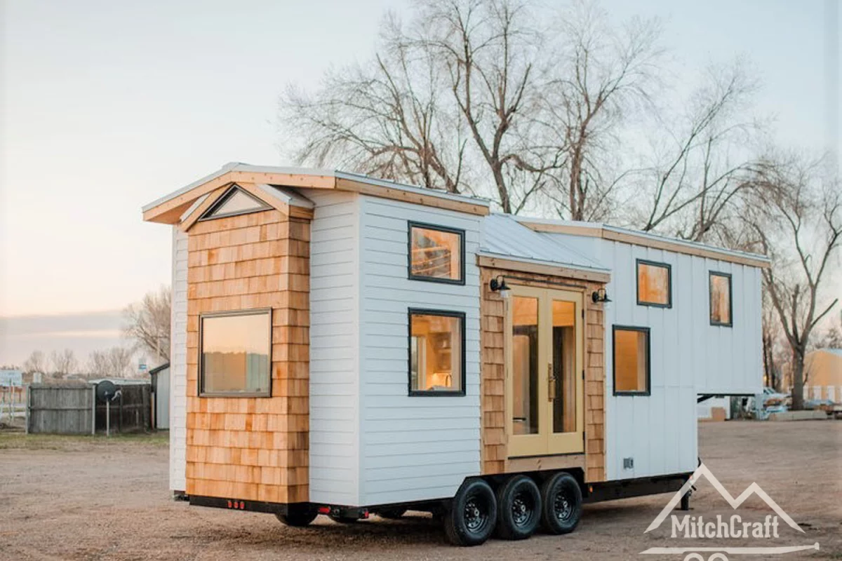 The quaint exterior is clad in white-painted timber and wooden shingles, while steel is the material choice for the roof and window frames