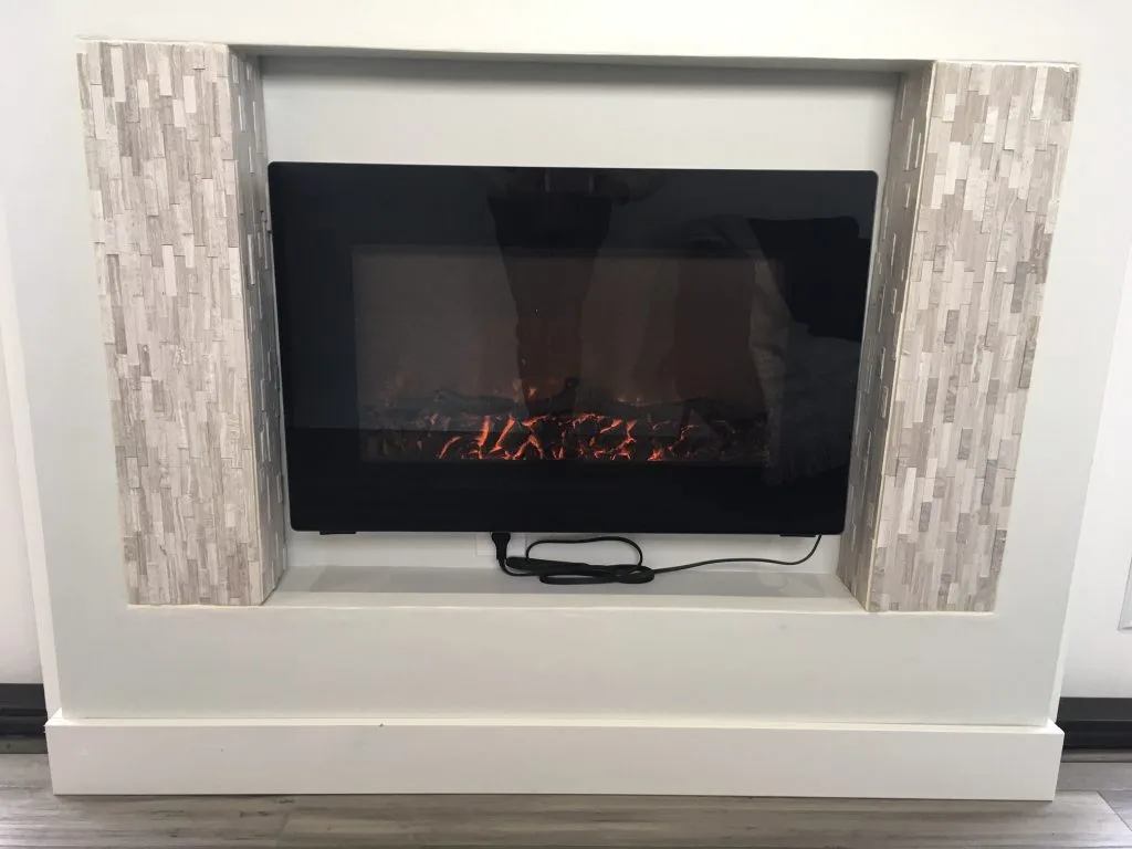 The Intellectual Tiny Home is heated by an electric fireplace in the living room, plus a flat panel heater in the bedroom