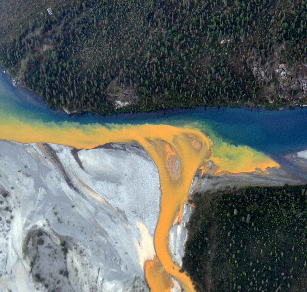 An aerial view of the Kutuk River in Alaska's Gates of the Arctic National Park that looks like orange paint spilling into the clear blue water