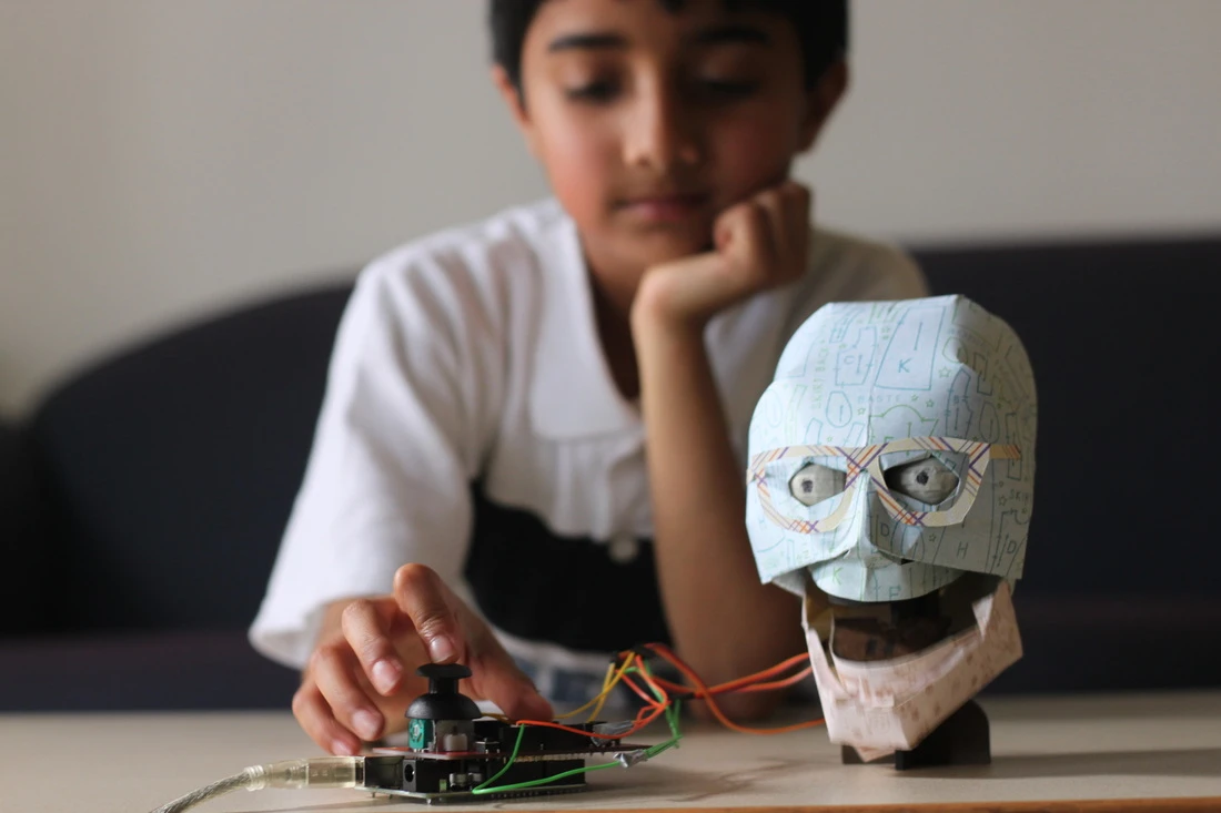 TJ* (seen here with an optional paper "skin") is a robotic human head that is controlled in real time or in response to code, provided by the user