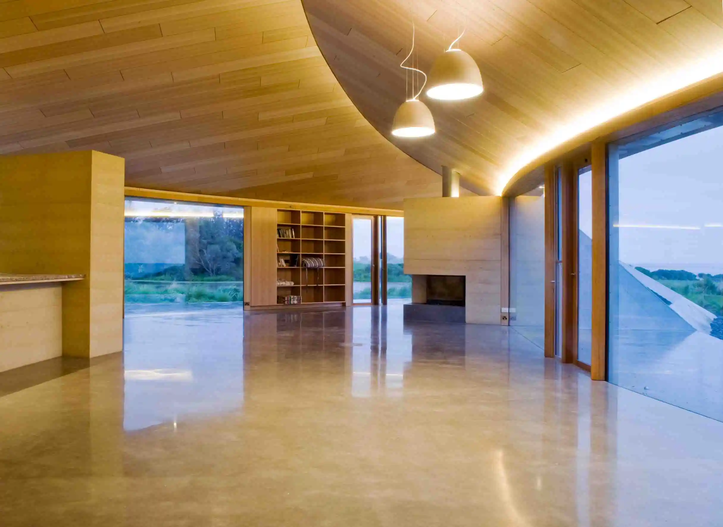 The home’s modern and simple interior finishes include polished concrete floors and soft wood paneled walls and ceilings