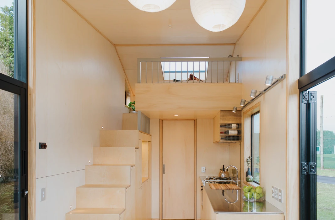 The First Light Tiny House has one bedroom, which is accessed by storage-integrated staircase