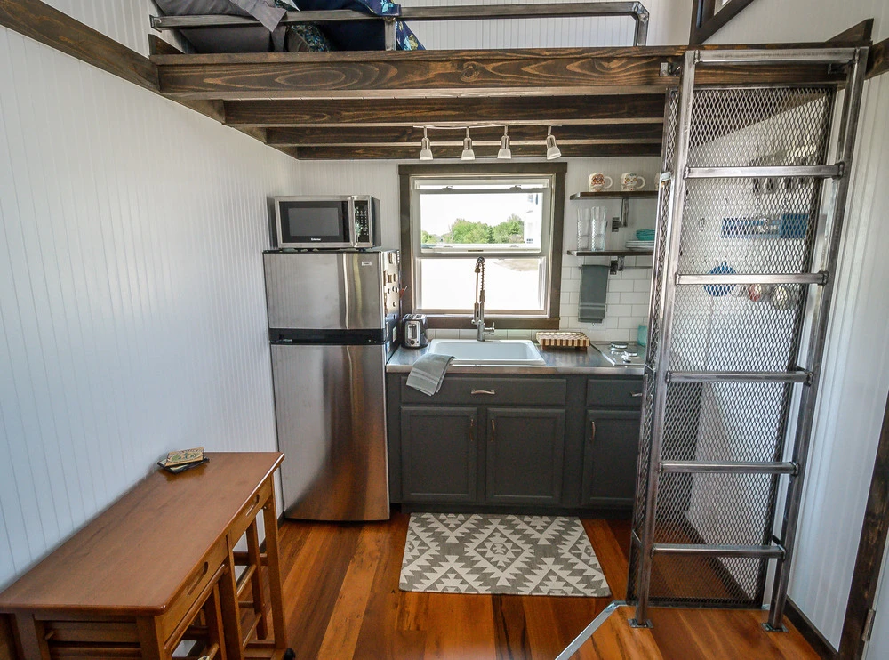The kitchen and sleeping/storage loft above, which is reached via custom ladder with integrated storage