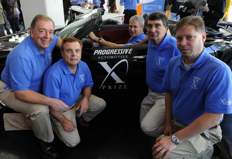 Qualified team AMP CEO and team leader Steve Burns takes the wheel of the AMP Sky roadster surrounded by fellow AMP team members