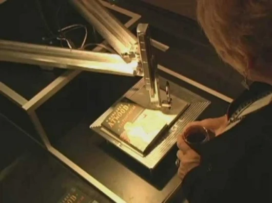 A recipient watches Atwood's message inscribed on her book. Image by Unotchit.