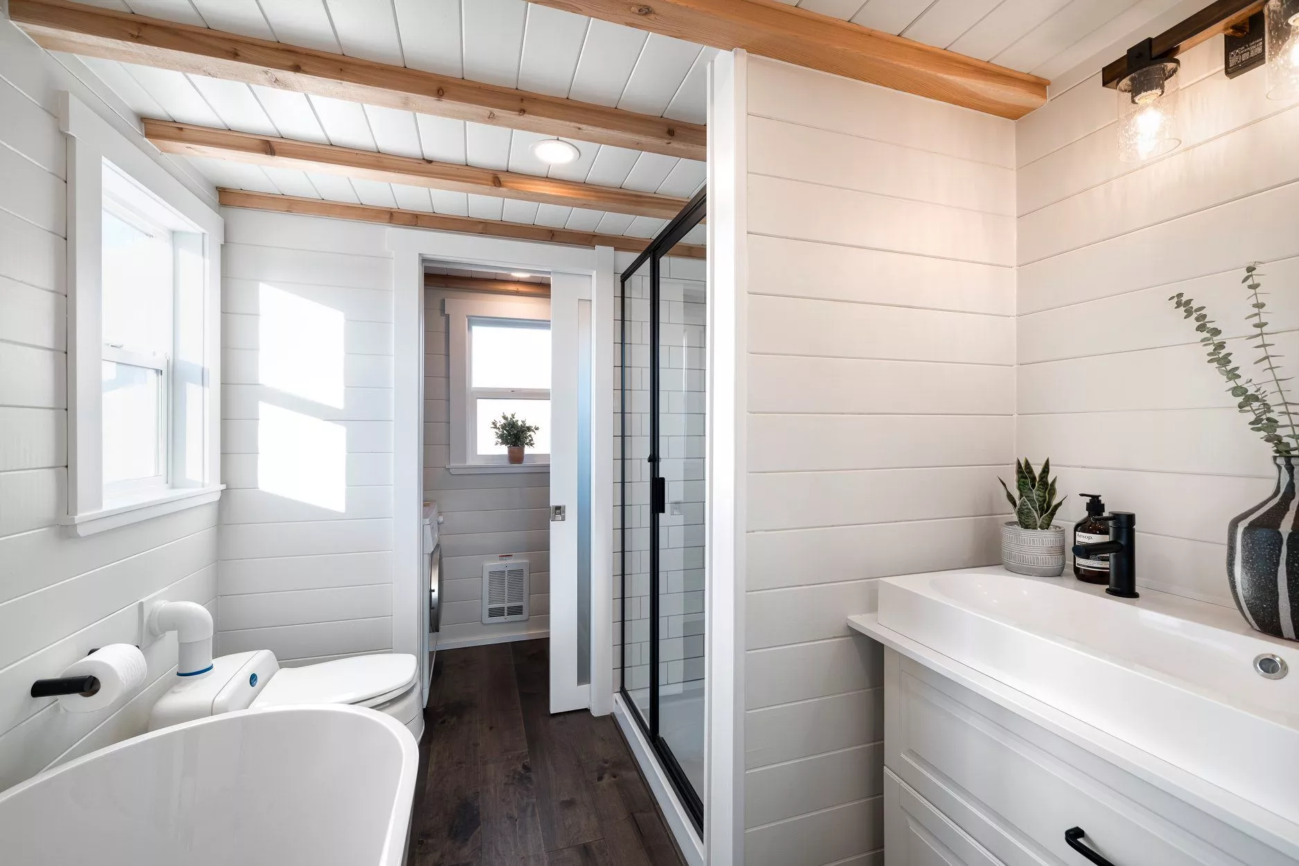 The 34ft Eco-Friendly Tiny House RV's bathroom connects to a small washroom with washer/dryer