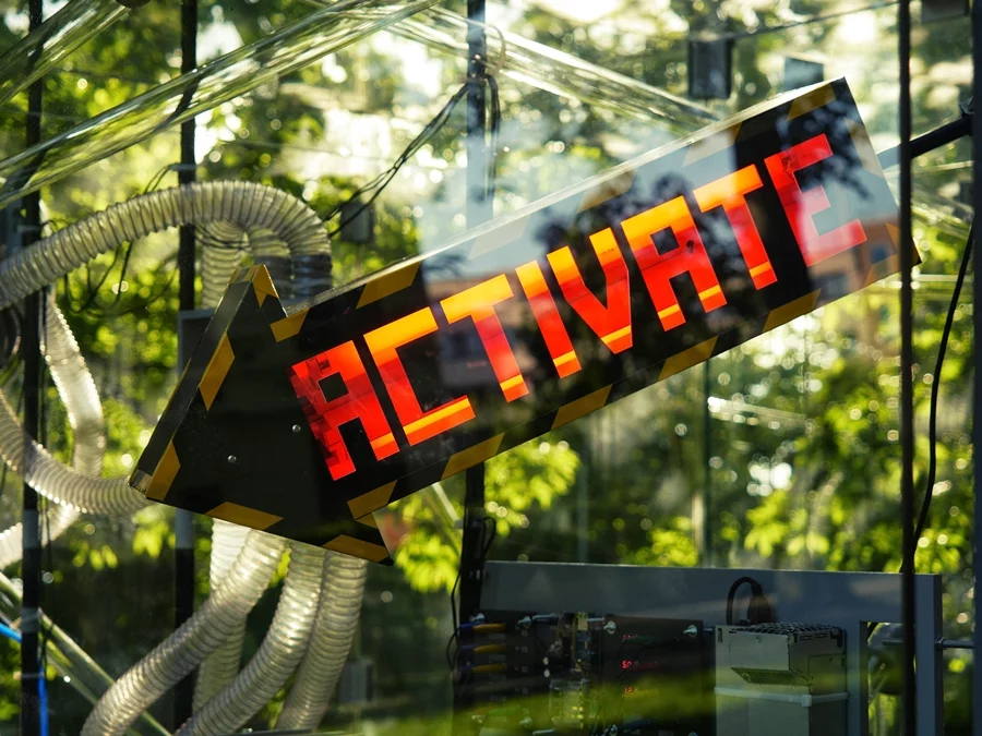 A large illuminated sign points to the touch sensor that individuals can use to activate the machine