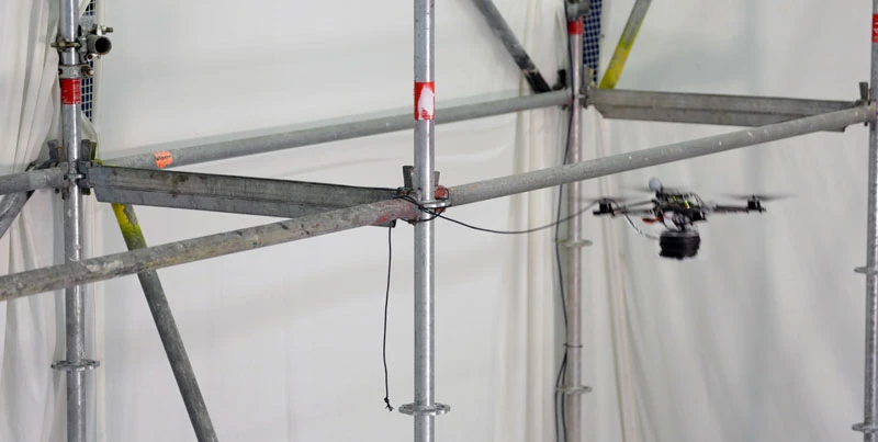 A fleet of quadcopters equipped with motorized spools moved autonomously between two scaffolds, laying out stretches of a light-but-strong rope called Dyneema as they went