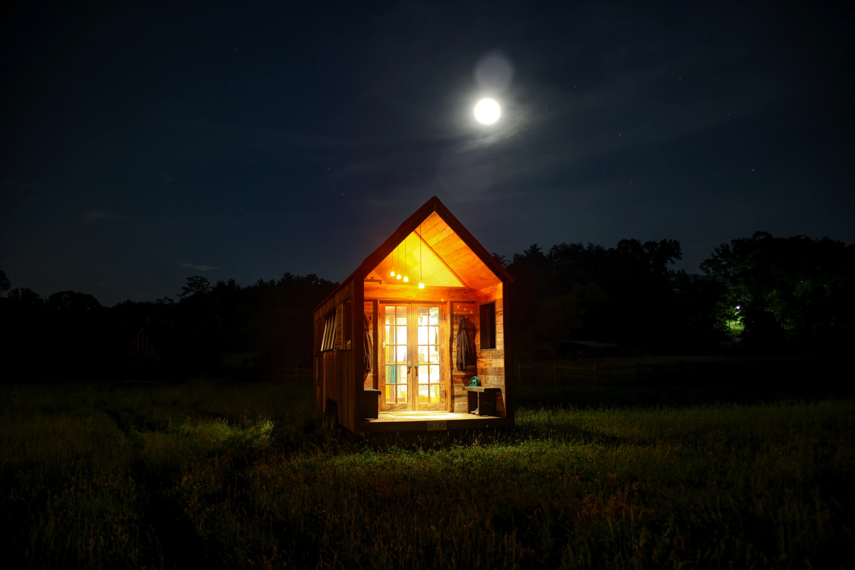 The home features a trailer base, frame and a colorful rustic exterior made from local and up-cycled hardwoods