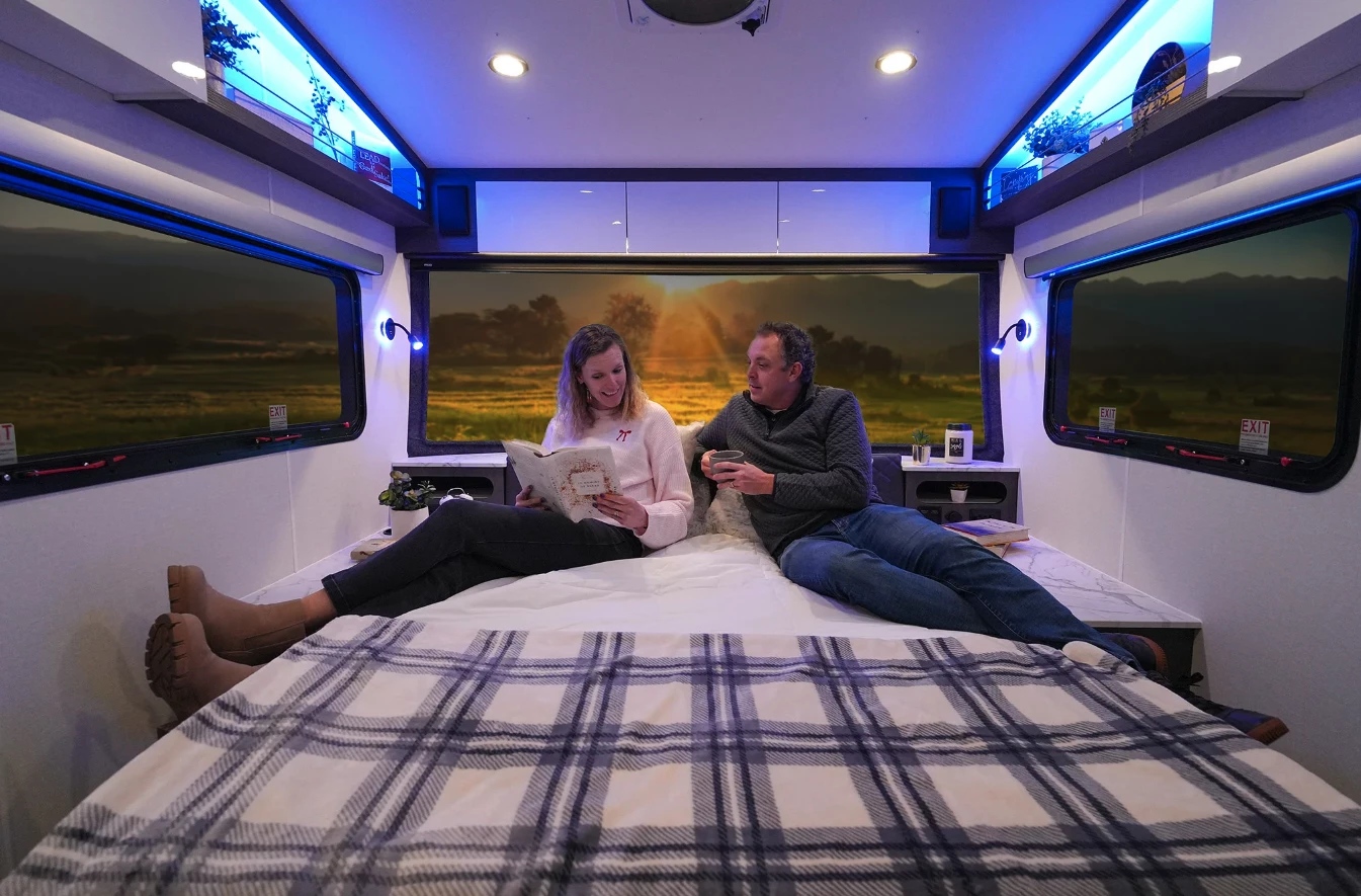 The queen bedroom provides a cozy escape with nightstands, overhead storage, a 32-in TV, ambient lighting and reading lights