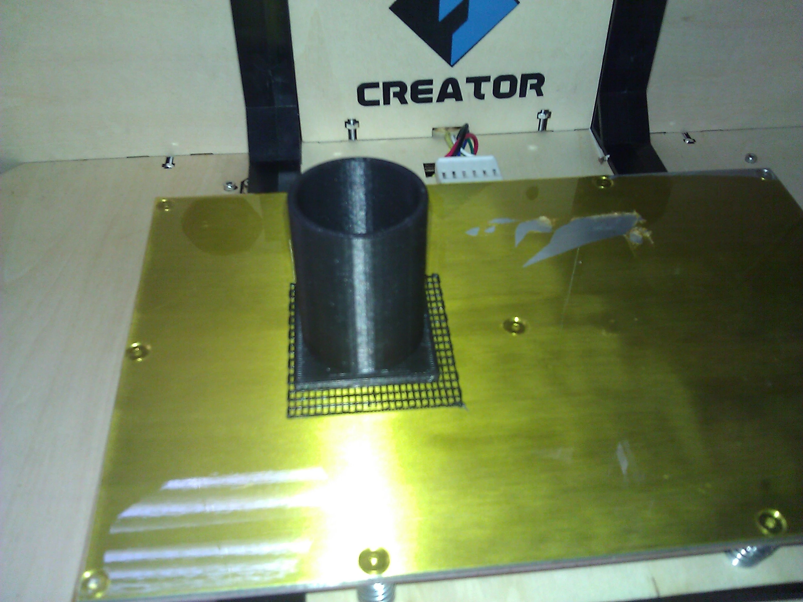 The first object I printed is this test cylinder. Notice the "raft" – a grid of plastic laid down by the printer to help stick the print to the platform. The platform is also heated to prevent warping (Photo: Gizmag)