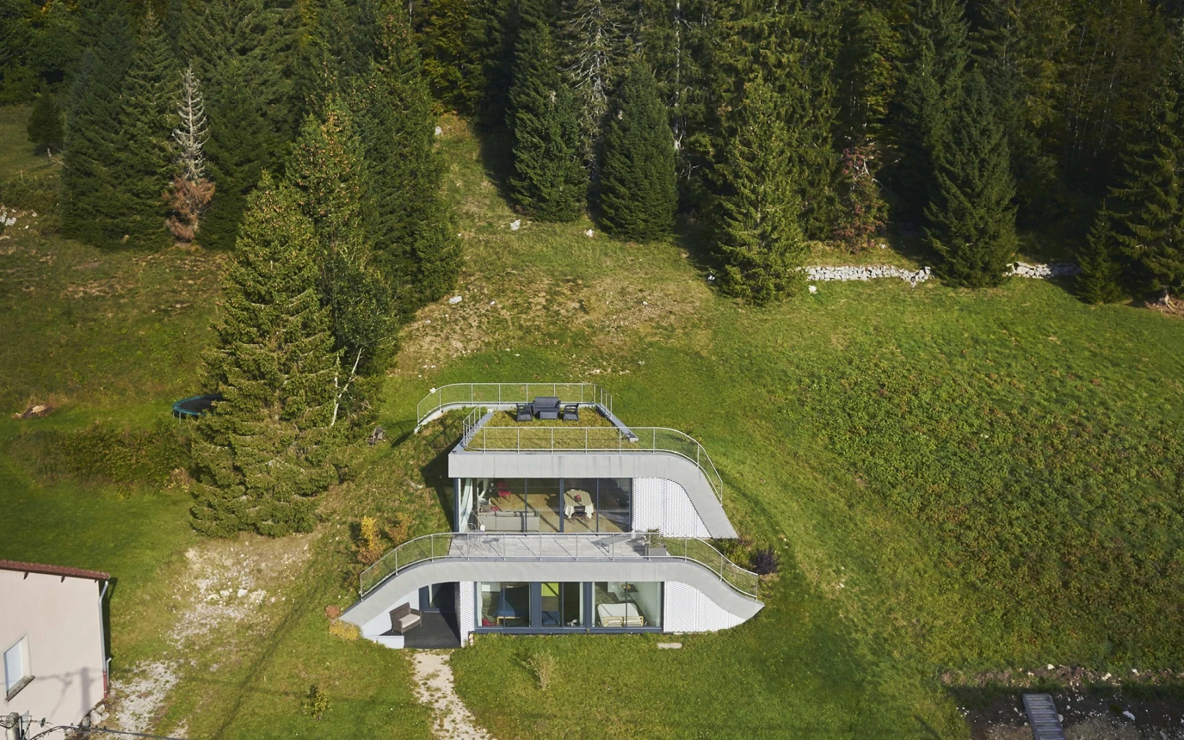 In France sits Casa Jura, a residential home built into the surrounding hill leaving just a couple of small outcrops to allow light in