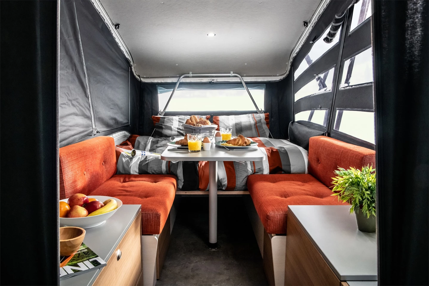 The new semi-fixed bed floor plan has the kitchen directly inside the entry way, a small convertible dinette farther ahead, and the fixed part of the bed in the very front
