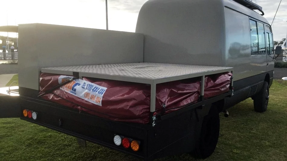 The Toyota Coaster 4x4 camper van includes a small flatbed for hauling an ATV or bikes