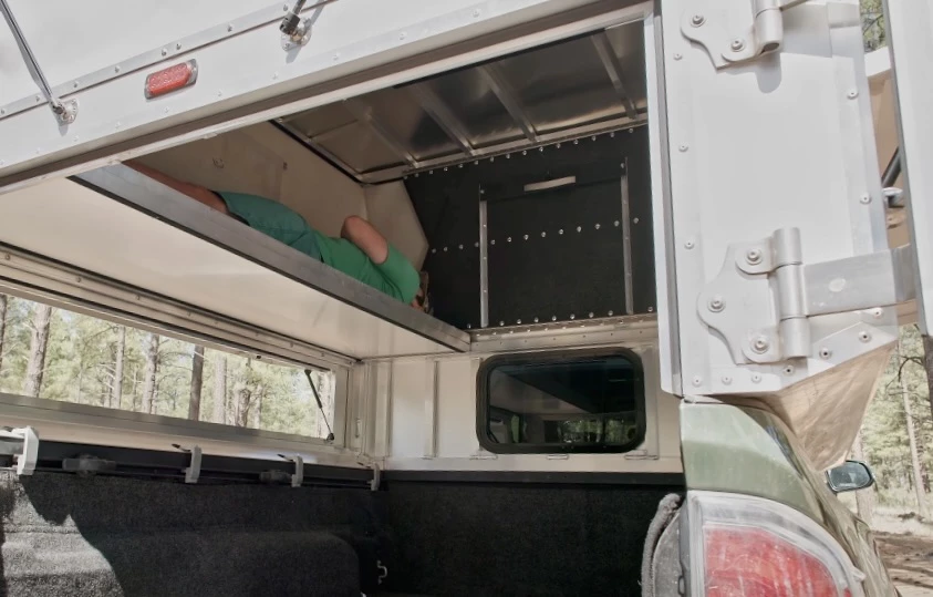 Lying down on one of the longitudinal sleeper platforms inside the midsize truck Bivy Chubby - the midsize variant doesn't offer enough width to lie transversely, but the 6-foot bed provides the length; alternatively a full-size model will provide 75 inches of width