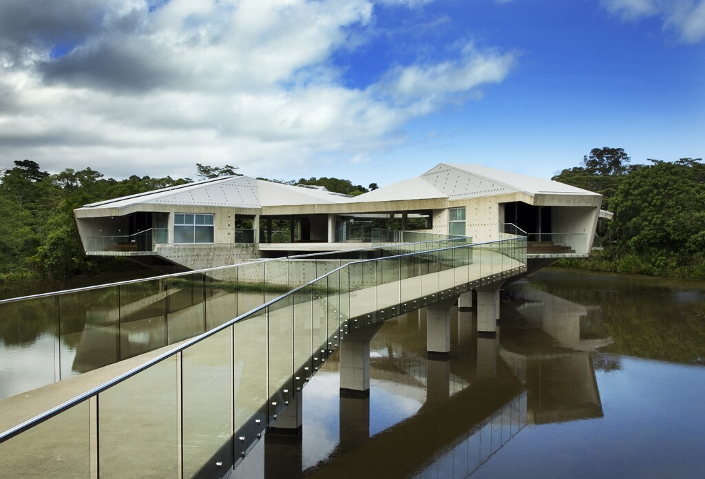 Visitors reach the house on a raised walkway that stretches over the pond waters to dry land