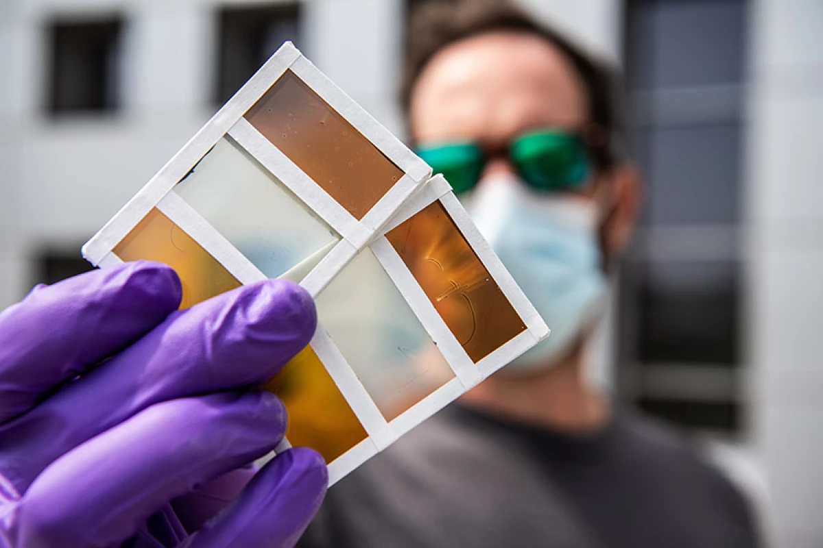 Researcher Lance Wheeler holds samples of the team's new thermochromic photovoltaic windows, which can switch colors in response to heat and generate electricity from sunlight